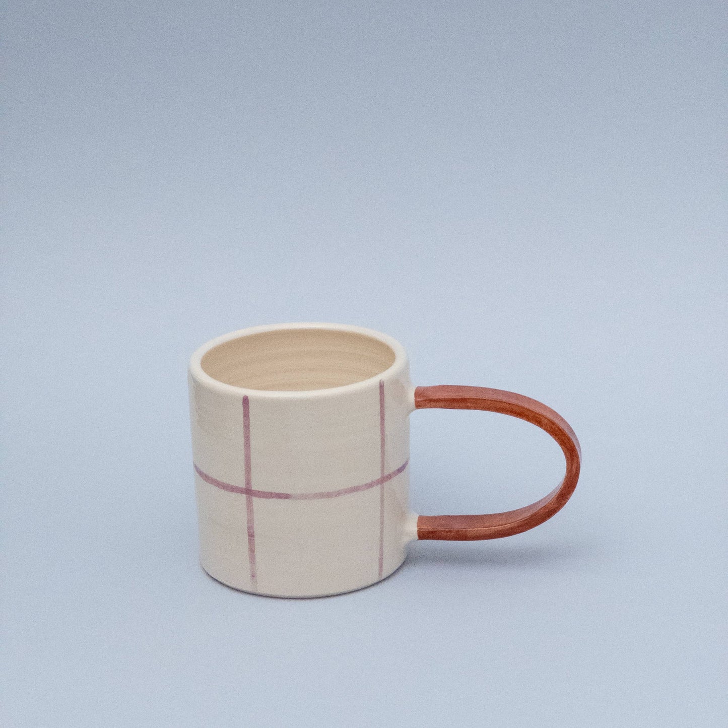 Karierter Becher mit rotem Henkel